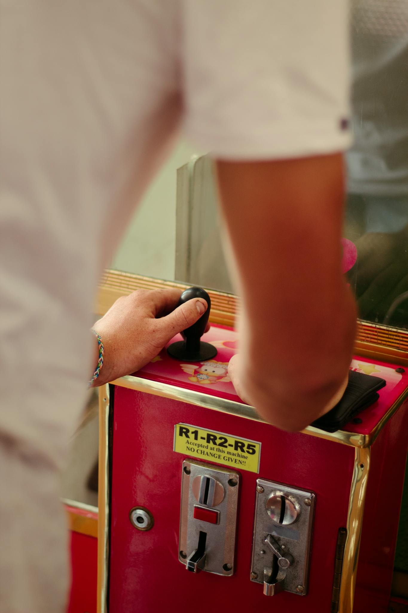 Close-up of a person playing an arcade game using a joystick, capturing leisure and concentration.